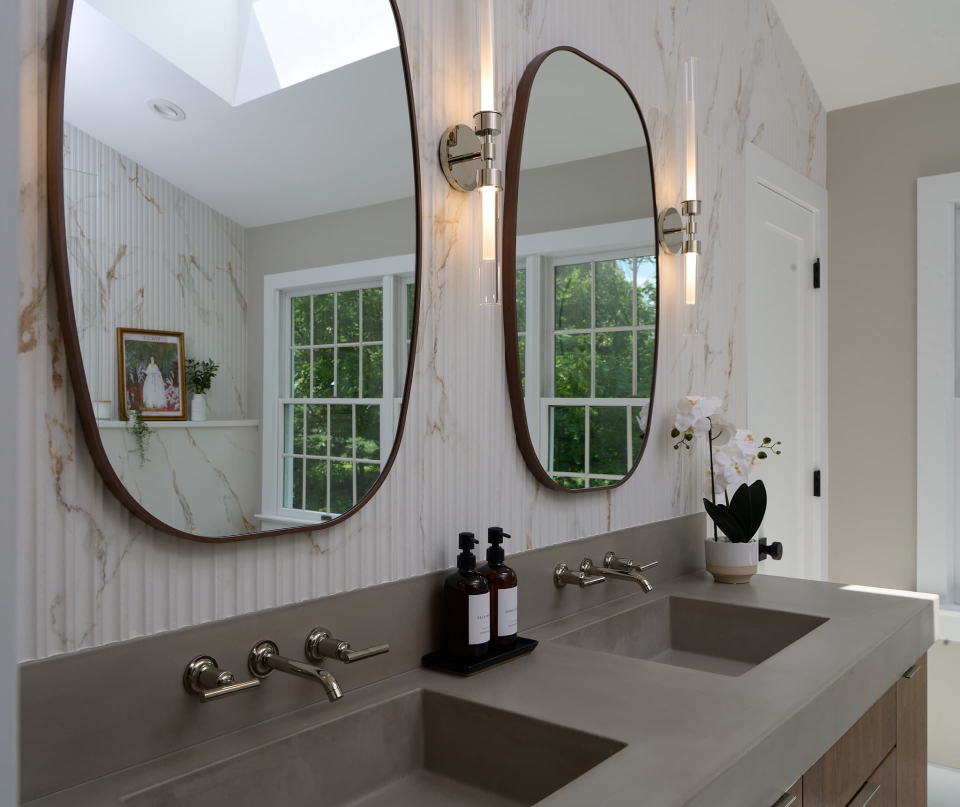 Rounded walnut mirrors and tube sconces hung over a concrete vanity in a Bucks County PA bath remodel