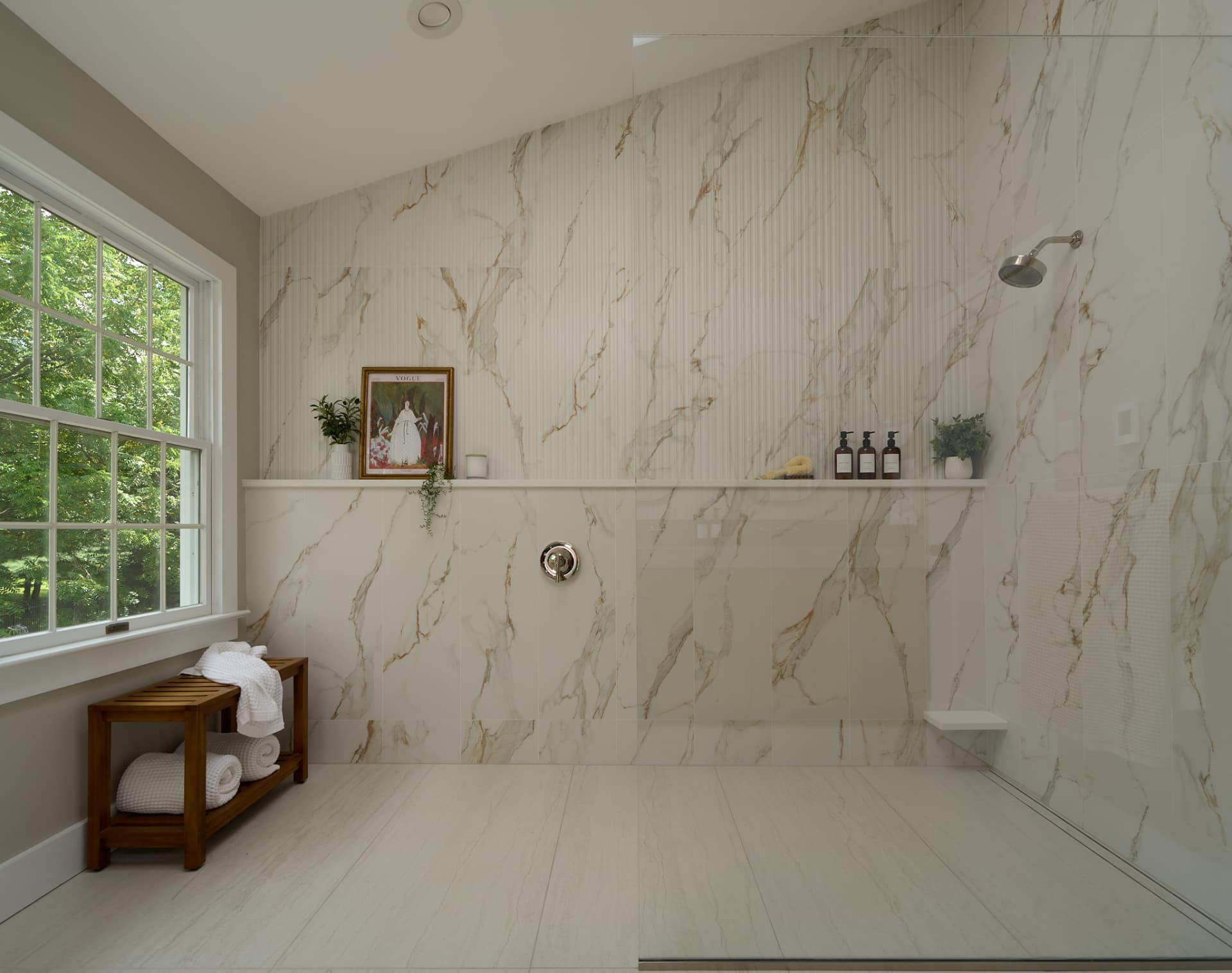 Curbless marble shower with a teak bench built into a primary bathroom remodel in Bucks County PA